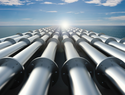 Vast number of big meetal pipes going into the horizon with the ocean and sun in background.