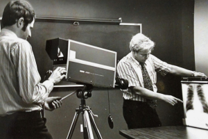 Old black and white photo of a person behind an old camera zooming in on an xray of a chest