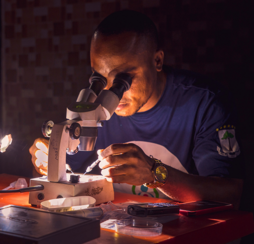 Man looking in a microscope at night with lights in Equatorial Guinea.