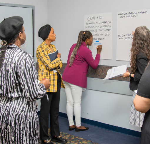 Women writing words on a large notepad during a conference.