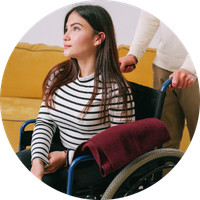 Photo of a woman sitting in a wheelchair in a clinical setting.