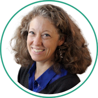 Woman with curly, mid-length hair and blue and black shirt smiling at camera.