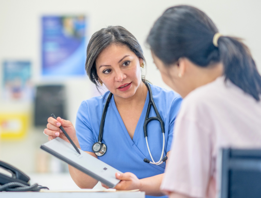 A health care worker talking to a patient at a desk with papers