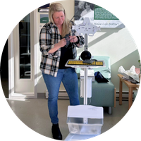 Woman putting together a stand with a large tablet screen on it.