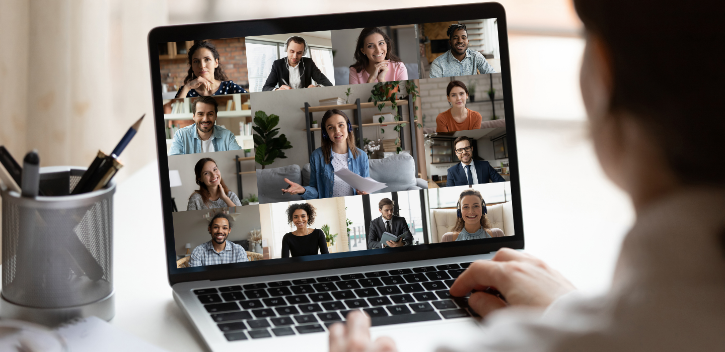 A man talking with other people on a virtual meeting at a computer.