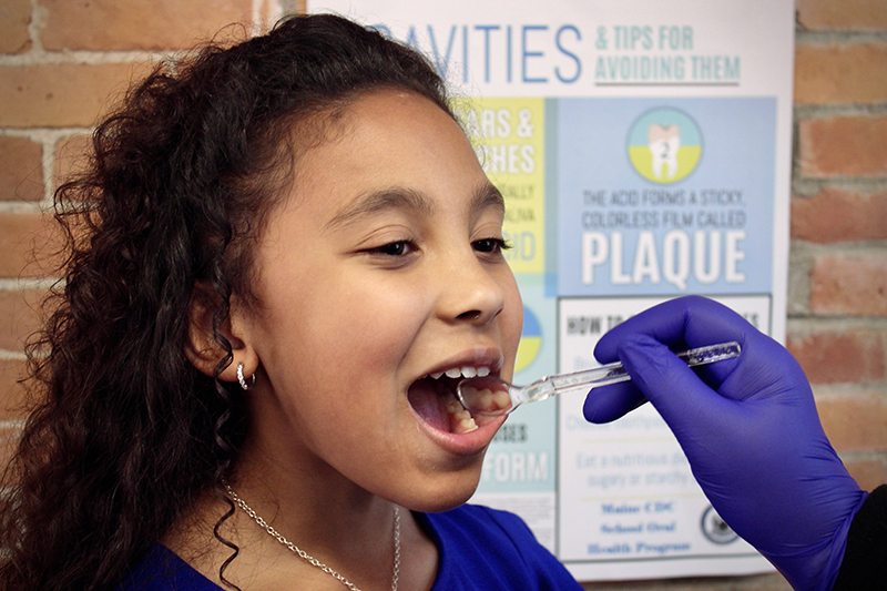 Conducting a dental exam of a child in Maine.