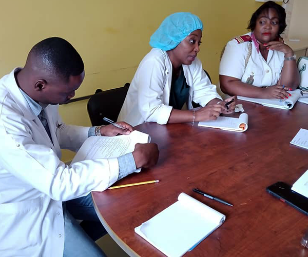 Image of three people in health care attire sitting at table discussing findings.