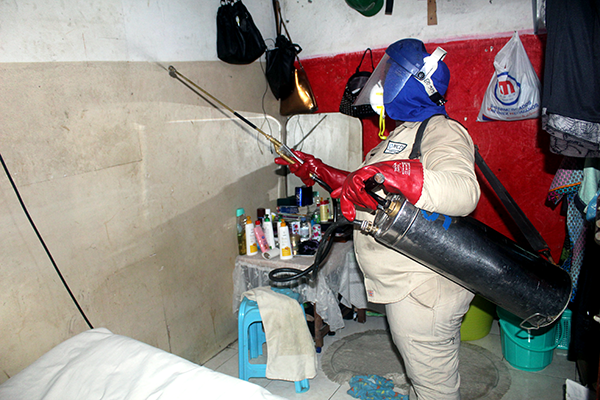 Worker sprays the inside of a residence on Bioko Island to help prevent malaria.