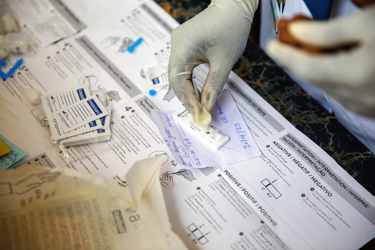 The lab technician takes the collected blood sample and smears it in a rapid diagnostic test on a table.