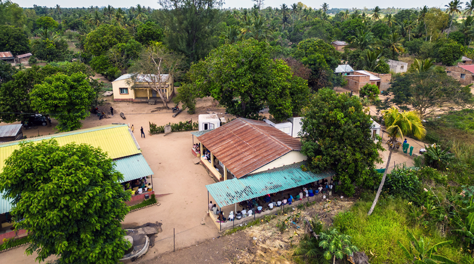 Aerial photograph of a community clinic with people sitting outside the clinic.