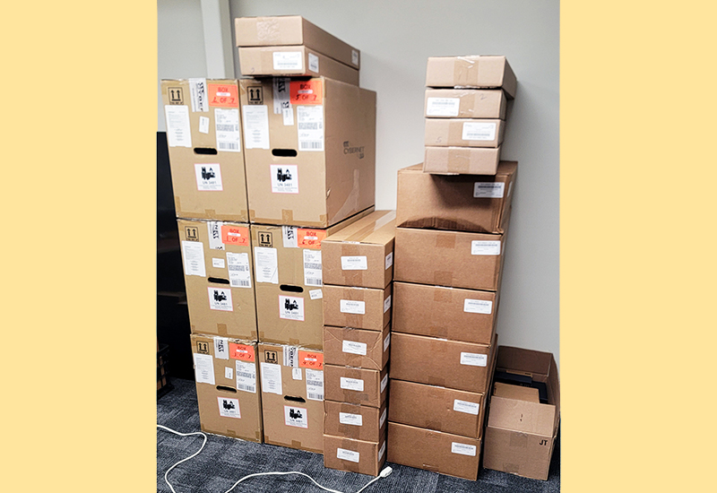 Stack of brown boxes up to the ceiling filled with telehealth equipment ready to be set-up.