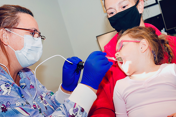 Sherry inspecting child's mouth as part of biannual oral health screenings at Maine public schools.