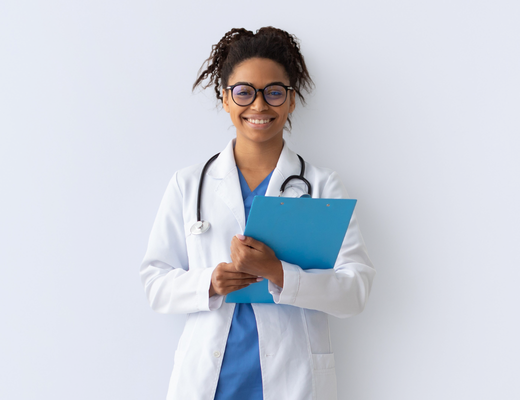 A smiling doctor stands holding a folder, with a stethoscope around her neck.