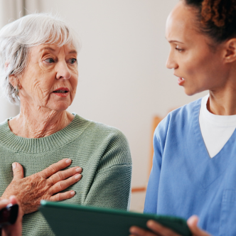 Photo of an older woman with disabilities talking to a provider over a clipboard.